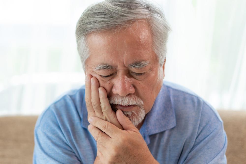 man holding jaw from pain during a dental emergency