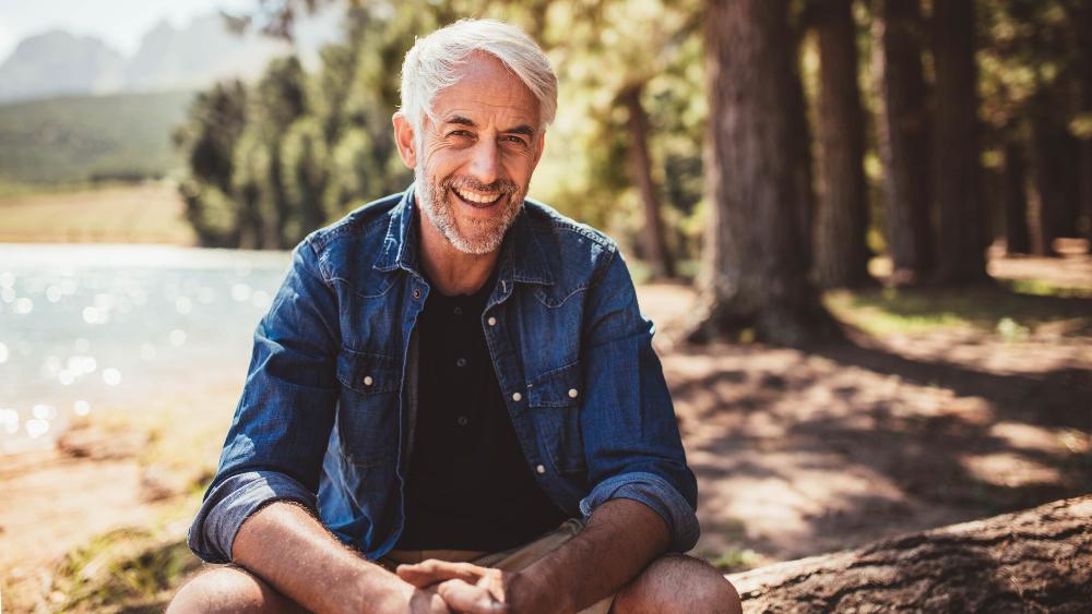 middle-aged man smiling while sitting near a lake