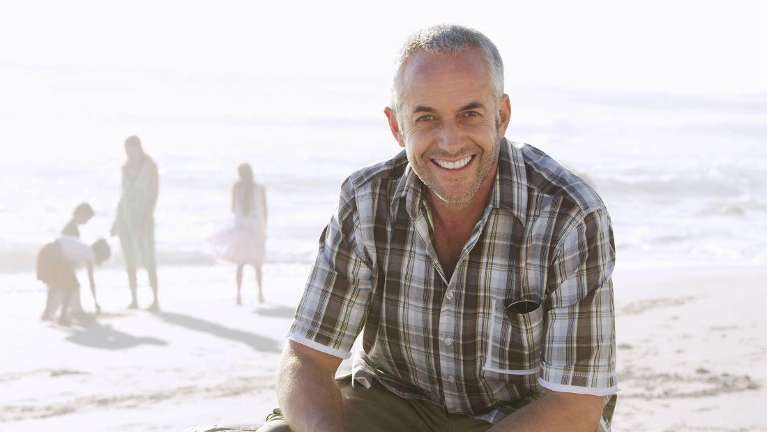 man smiling while sitting at the beach