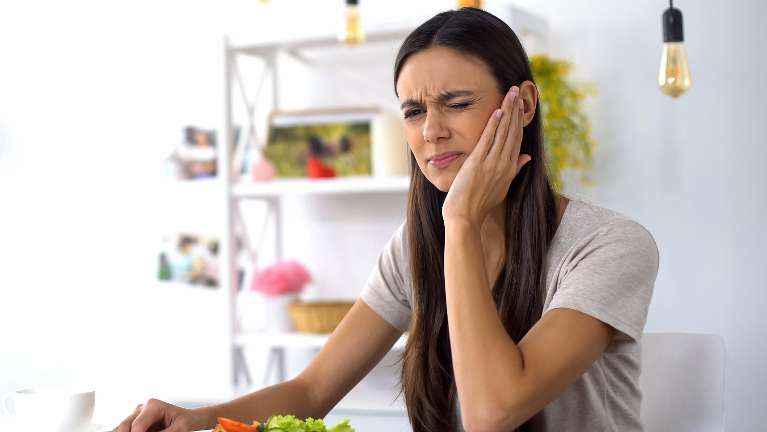 woman holding jaw from tooth pain during a dental emergency in coeur d'alene