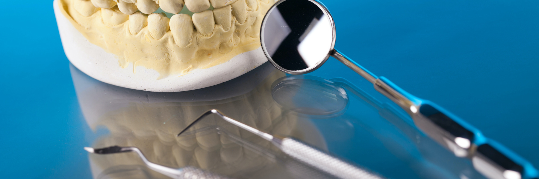 Dental mold and surgical instruments on blue surface representing complex dental surgery procedures