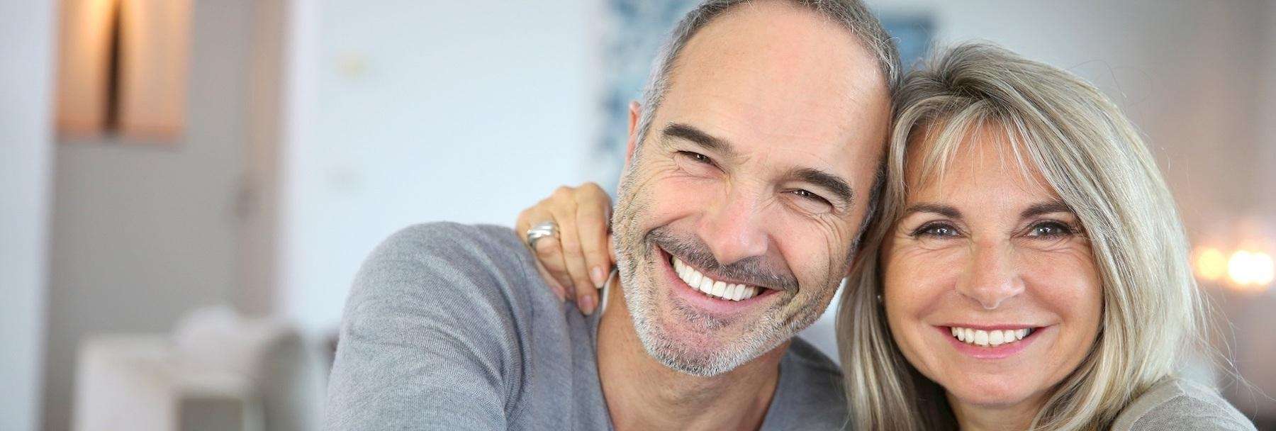 middle-aged couple smiling after getting dental crowns